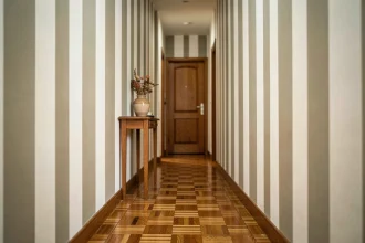 Couloir étroit peint avec des bandes verticales blanches et grège pour créer un effet d'allongement visuel