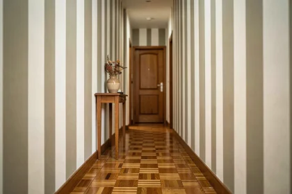 Couloir étroit peint avec des bandes verticales blanches et grège pour créer un effet d'allongement visuel